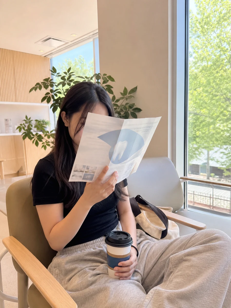 A woman reading a dental insurance leaflet in a bright clinic waiting room